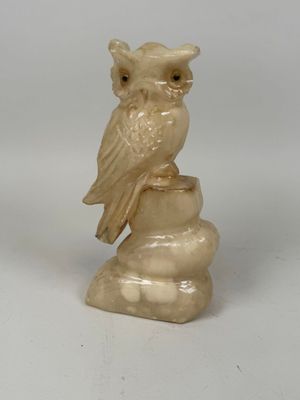 a small statue of an owl sitting on top of a rock