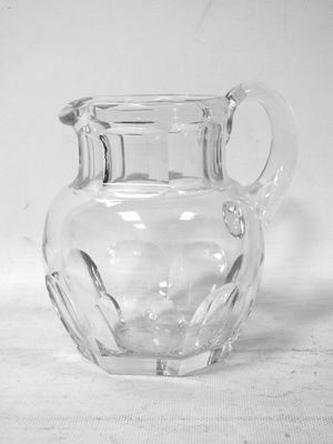 photographie en noir et blanc d'un pichet en verre transparent posé sur une table