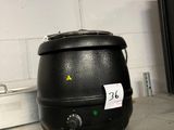une casserole noire posée sur une étagère, à côté d'un micro-ondes