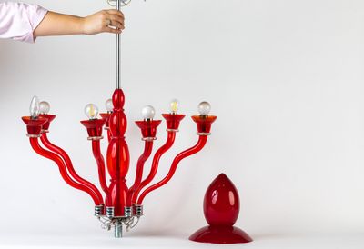 a woman standing next to a red chandelier and a red candle holder