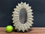 an apple sitting next to a mirror on a table