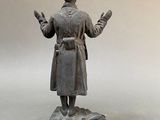 statue of a man in a trench coat standing on a marble base