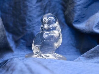 a glass owl figurine sitting on a blue cloth