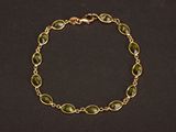 un bracelet en or orné de perles de verre vertes sur fond noir