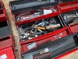 two red boxes with tools in them on the floor