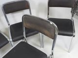 four black chairs sitting in a row on a white surface