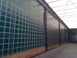 a long room with a green wall and a metal fence