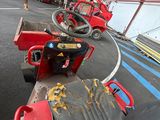a red tractor parked in a warehouse with other vehicles