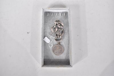 un collier en argent avec une pièce, dans un coffret en argent