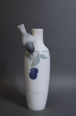 un vase blanc surmonté d'un oiseau bleu