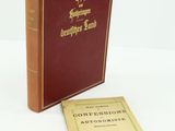 un vieux livre posé sur une table blanche à côté d'un livre