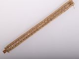 gros plan d'un bracelet en or sur une surface blanche
