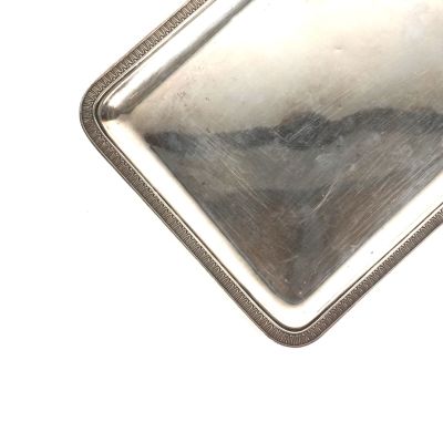 un plateau argenté avec une poignée sur une surface blanche