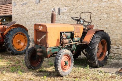 deux vieux tracteurs garés devant un bâtiment