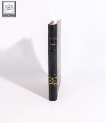 an old black book sitting on top of a table next to a white wall
