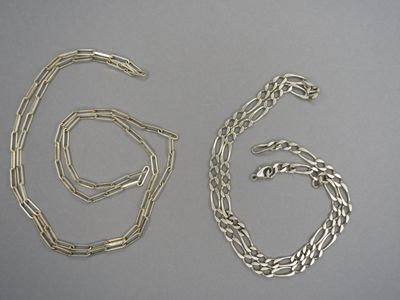 deux morceaux de chaîne en argent sur une surface grise