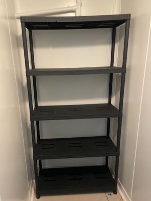une étagère noire à quatre tablettes, placée dans un coin de la pièce