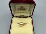 une photo d'une bague en or sertie d'une perle, dans un écrin en velours