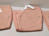 three pairs of pink pants sitting on top of a white table