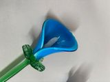 a blue flower with a green stem on a white surface