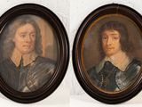 Deux portraits, celui d'un homme et celui d'une femme, sont accrochés au mur.