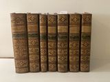 six vieux livres sont alignés sur une surface blanche