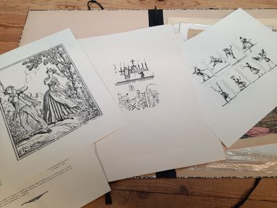 Plusieurs dessins représentant des personnes et des animaux sont posés sur une table.