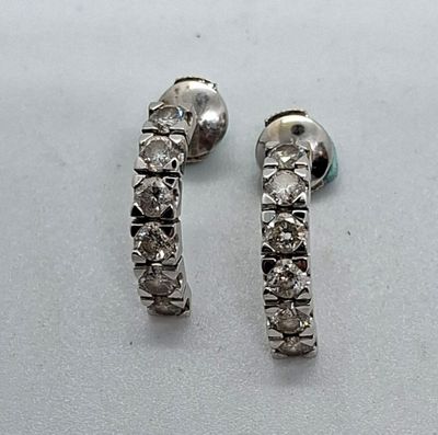 une paire de boucles d'oreilles créoles en diamant posées sur une surface blanche