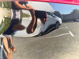 a reflection of a man riding a skateboard on the side of the road