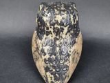 a close up of a black and white owl statue on a black surface