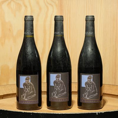 three bottles of wine sitting on top of a wooden barrel