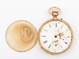 a gold pocket watch sitting next to a gold coin