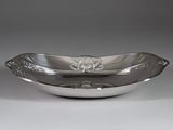 a silver plate with a flower design on it on a white surface