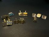 five pairs of cufflinks and two cufflinks on a table