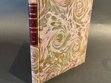 an old book with a pink cover sitting on top of a table