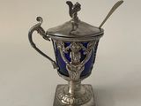 a silver cup with a spoon on top of it on a white surface