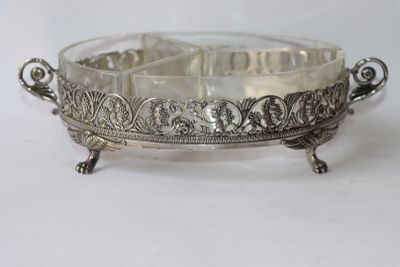 an antique silver plate with ornate design on it on a white surface