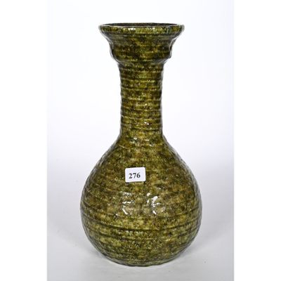 un vase vert posé sur une surface blanche