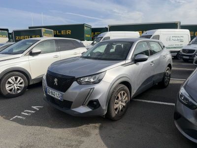 de nombreuses voitures garées sur un parking, avec une camionnette en arrière-plan