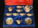 nine cups and saucers in a box on a blue cloth