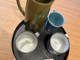 two cups and a pitcher on a tray on a table