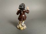 figurine of a boy in a brown coat and hat