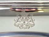 a silver plate with a crest on it and a silver plate with a crest on it