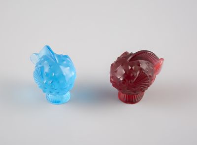 deux figurines en verre de couleurs différentes posées sur une surface blanche