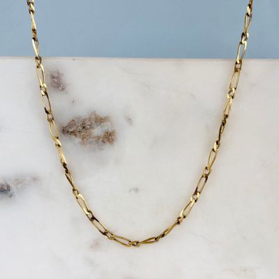 un collier à chaîne en or posé sur une surface en marbre