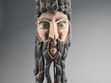 une image représentant un masque muni d'une barbe, posé sur un socle