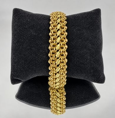 a close up of a gold chain bracelet on a black pillow
