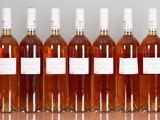 six bottles of wine are lined up on a wooden table