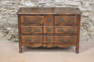 a wooden dresser with many drawers on it in front of a stone wall