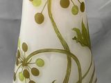 un vase blanc orné de motifs verts et marron